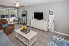 Relax in this stylish living room with a sofa, armchair, and coffee table, offering a view of the city outside.
