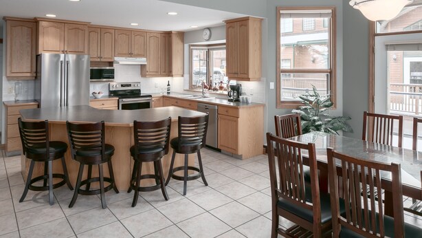 Una cocina moderna con armarios de madera, electrodomésticos de acero inoxidable y una isla grande con taburetes de bar.