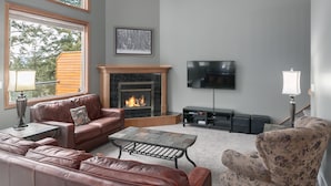 Una sala de estar con chimenea, sofás de cuero, una mesa de centro y un televisor montado en la pared.