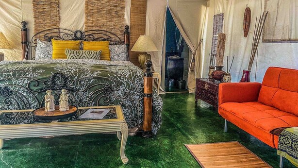 Een tentkamer met een bed, een bank en een tafel met decoratieve spullen.