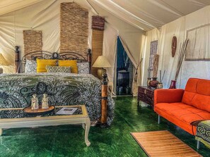 A tented room with a bed, a sofa, and a table with decorative items. - Pet Friendly Zen Luxury Glamping tent (Irwin)