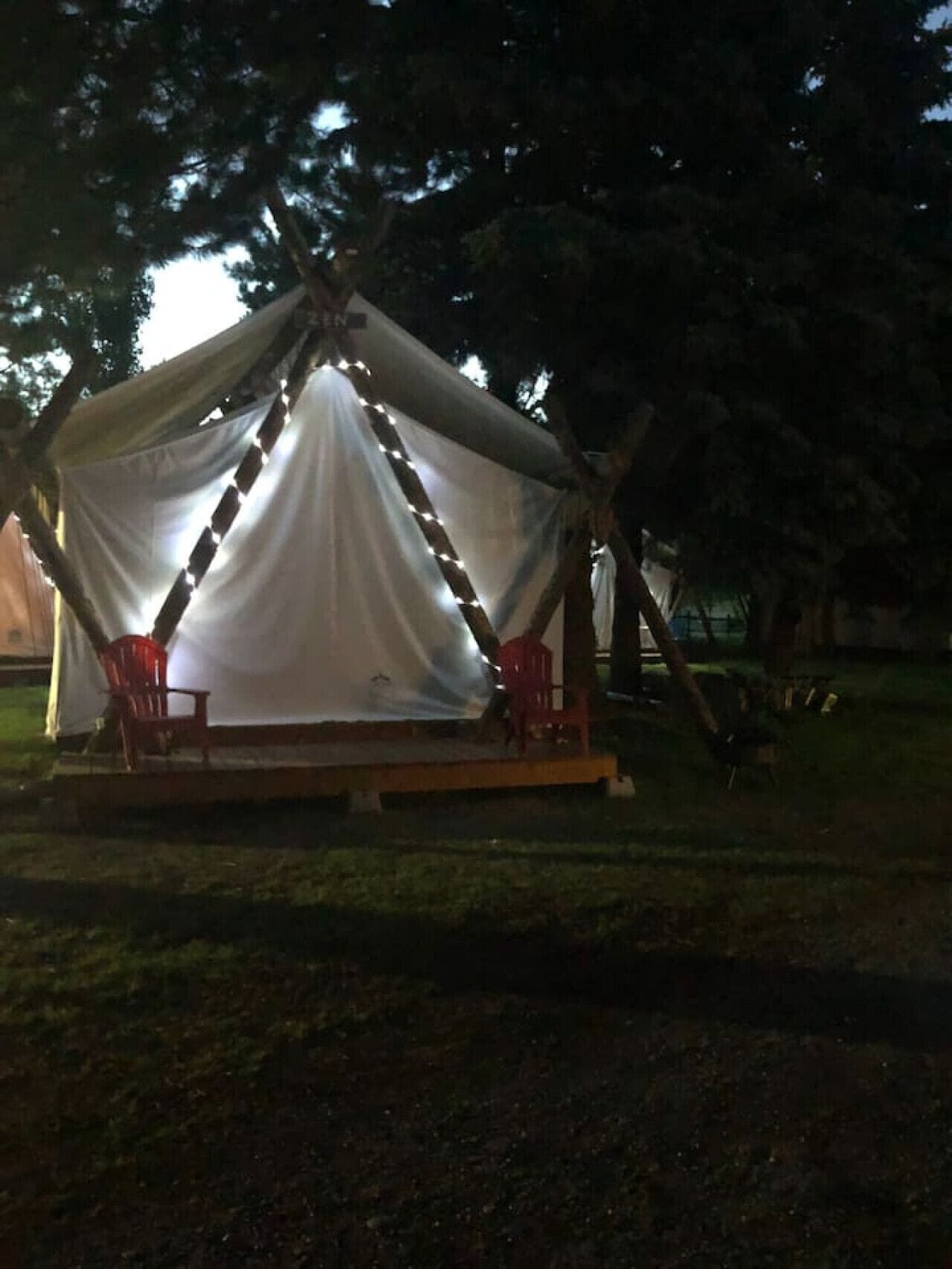 A tent with a covered porch and two chairs.