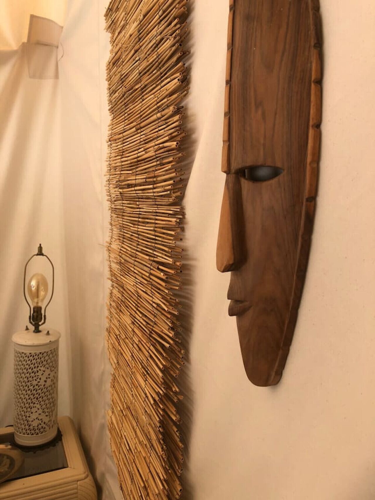 Un mur à la texture tissée et un masque en bois.