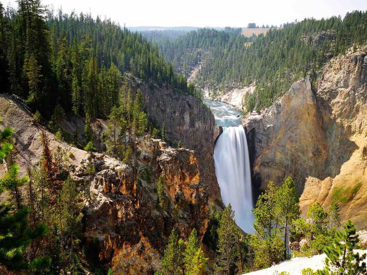 Un cañón con una cascada y un bosque denso.