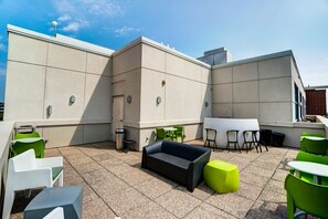 Relax on the patio with a black sofa, round table, and comfortable chairs.