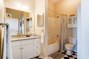 A bathroom with a shower, toilet, and vanity with a mirror.