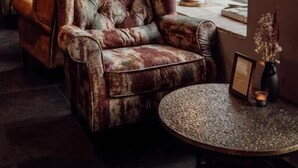 A cozy seating area with plush armchairs and a small round table, featuring a globe lamp and a vase with dried flowers. - Broederenklooster (Zutphen)
