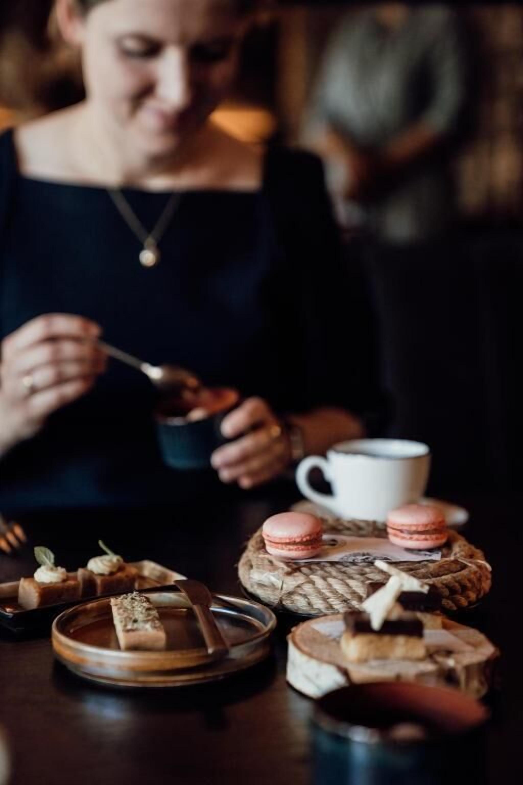 A person dining at a table with a cup and a plate of food.