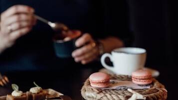 A person dining at a table with a cup and a plate of food.