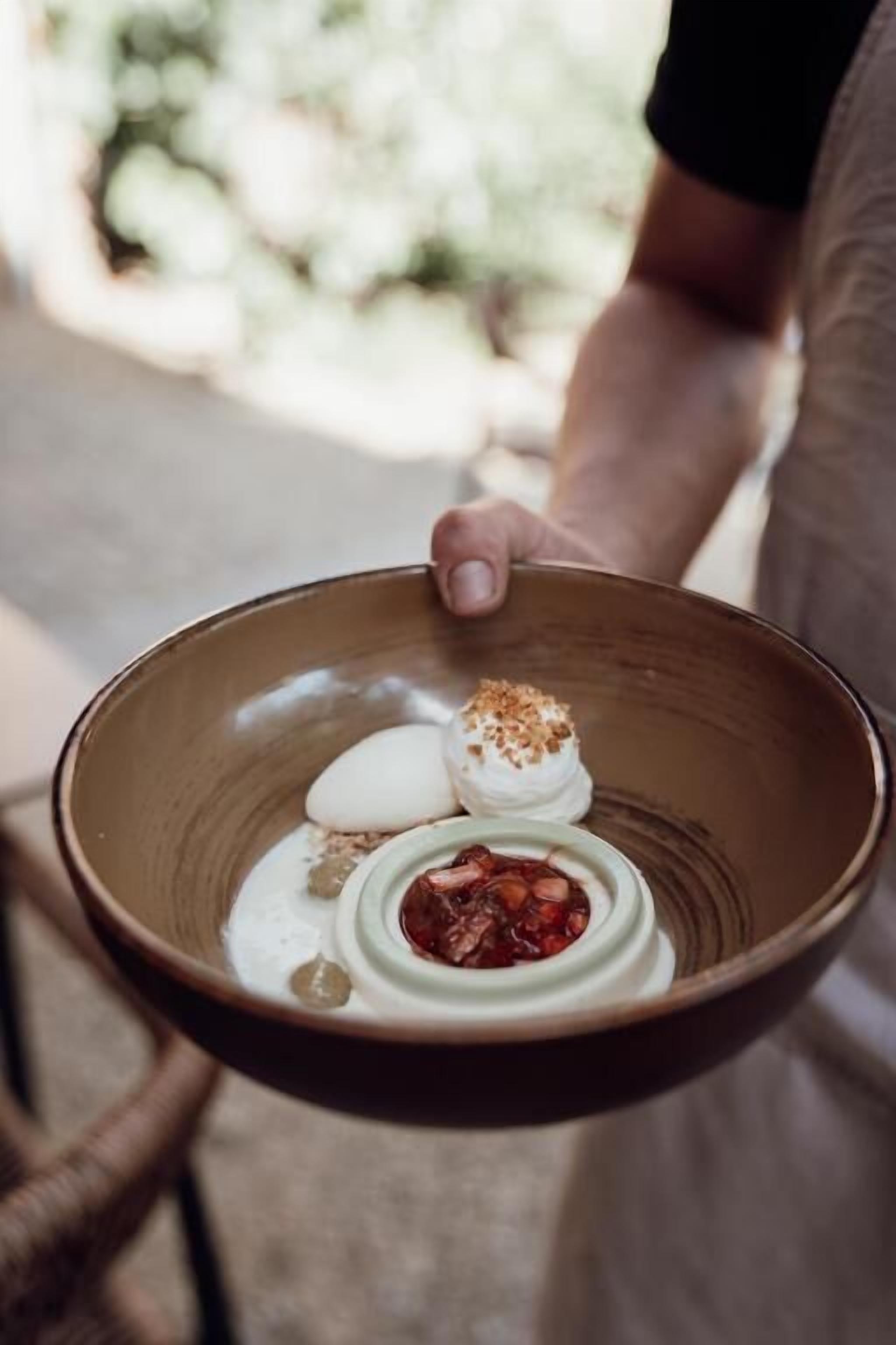 A person holding a bowl with a dessert.