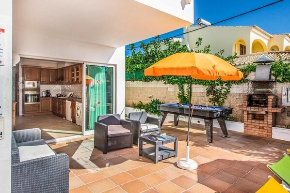 Un espace extérieur aménagé avec du mobilier de jardin, une table de billard et un barbecue.