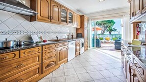 Una cucina con pensili in legno, cappa in acciaio inossidabile e zoccolo paraschizzi piastrellato.