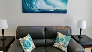 A living room with a black leather sofa, two patterned throw pillows, a large abstract painting on the wall, and two side tables with lamps. - Spacious 3/2/ condo located minutes from downtown area of Beautiful Tamarindo  (Tamarindo)