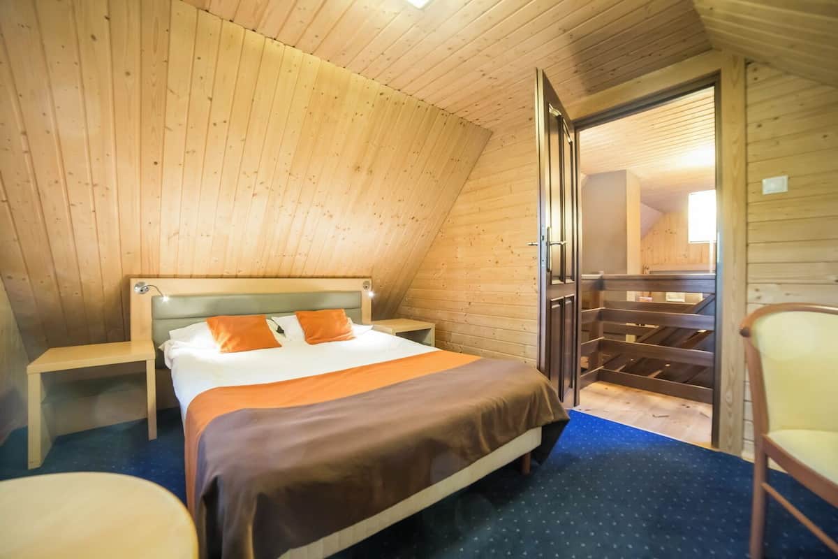 A cozy, wooden-paneled bedroom with a bed, nightstands, and a chair.