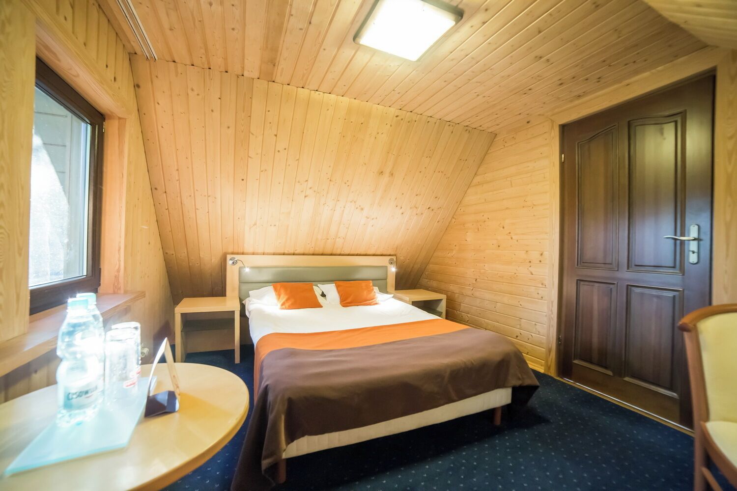 A cozy room with a bed, bedside table, and a window.