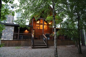 A log cabin with a stone chimney, wooden exterior, and a staircase leading to the entrance. - Lazy Pine Lodge: 4BR, 4BA, Sleeps 14 (Broken Bow)