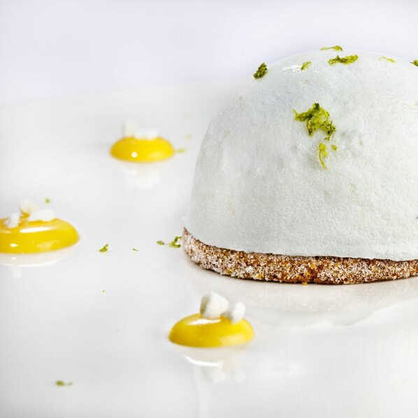 A dessert with a white dome shape, a brown base, and yellow sauce.