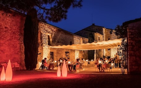 An outdoor dining area with stone walls and tables under a canopy.