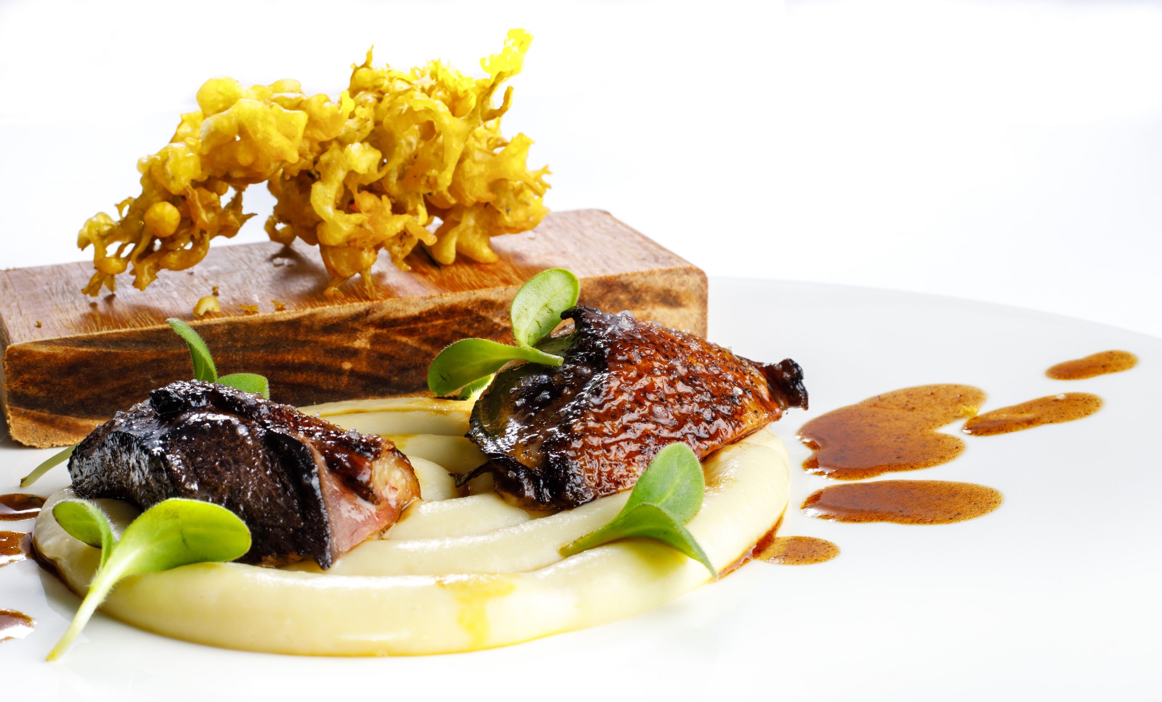 A dish with meat, vegetables, and sauce on a white plate.