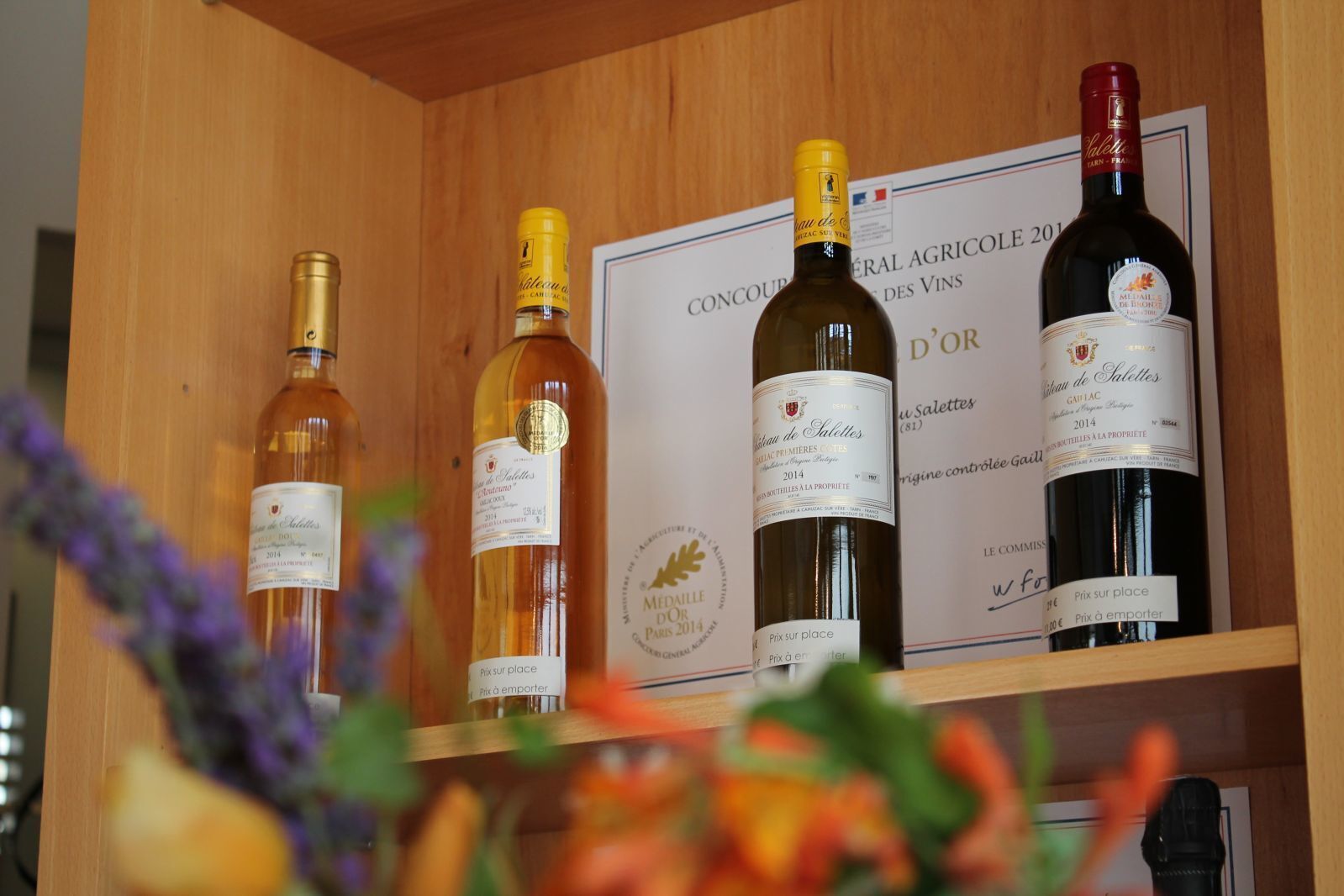Una botellera de madera con cuatro botellas de vino, cada una con etiqueta.