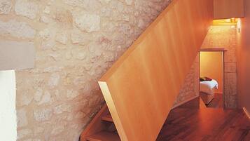 Una escalera de madera con un muro de piedra a un lado y piso de madera.