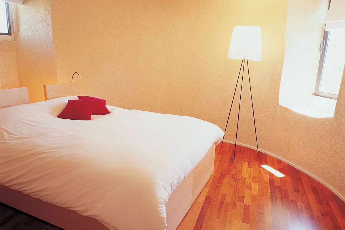 Une chambre à coucher avec un lit, une lampe sur pied et une fenêtre.