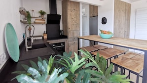 A modern kitchen with wooden cabinets, a black range hood, and a wooden dining table with benches. - 4 bedroom villa with heated pool and sea view, 5 minutes from the beach (LECCI)
