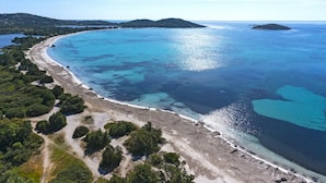 An aerial view of a coastal area with a sandy beach, clear blue waters, and green hills in the background. - 4 bedroom villa with heated pool and sea view, 5 minutes from the beach (LECCI)