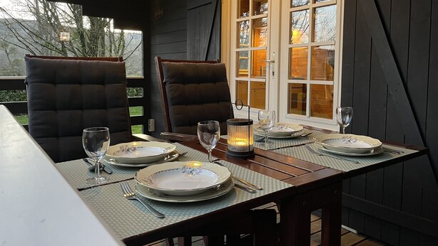A dining table set for two with dark upholstered chairs, a candle, and plates. - Gîte & Chambre d'hôte "Les Moulins au bord du lac" Morvan, France (Corancy)