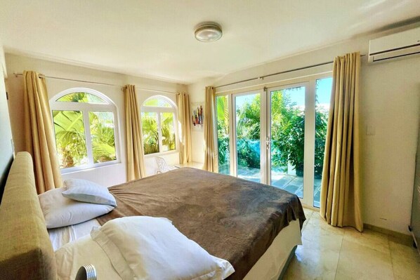 A bedroom with a bed, curtains, and large windows.