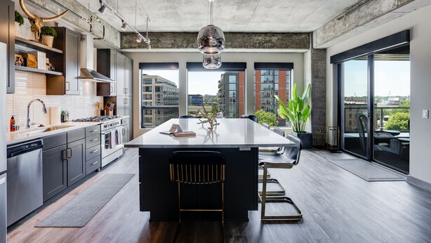 A modern kitchen with a large island, stainless steel appliances, and a view of the city through large windows. - MINNeSTAY* Sable 501 - Luxury Two Story Loft | North Loop | Target Center (Minneapolis)