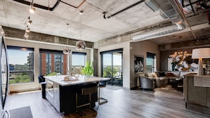 A modern kitchen with a central island, large windows, and a view of the city. - MINNeSTAY* Sable 501 - Luxury Two Story Loft | North Loop | Target Center (Minneapolis)