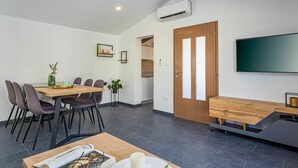 Un espace repas moderne avec une table en bois, des chaises et un téléviseur fixé au mur.