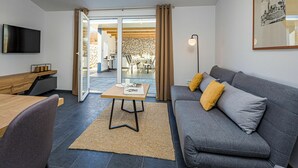 Un salon moderne avec un canapé gris, une table basse en bois et un téléviseur à écran plat fixé au mur.