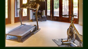 A home gym with a treadmill and stationary bike, large windows, and a view of the outdoors.
