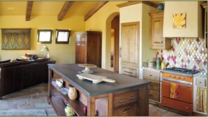 A kitchen with a stone floor, wooden furniture, and a built-in oven.
