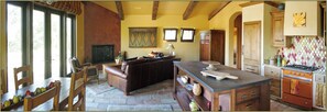 A kitchen with a stone floor, wooden furniture, and a built-in oven.