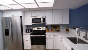 Une cuisine moderne avec des meubles blancs, des appareils en acier inoxydable et un plancher en bois.