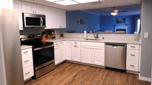 Une cuisine moderne avec des armoires blanches, des appareils en acier inoxydable et un plancher en bois.