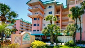 Un hôtel à plusieurs étages doté de balcons, de palmiers et d’une enseigne indiquant « The Beach Cottage ».