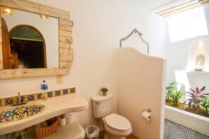Un bagno con lavabo piastrellato, WC e una piccola pianta sul serbatoio del water.