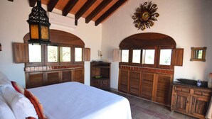 Un dormitorio con una cama grande, armarios de madera y ventanas arqueadas.