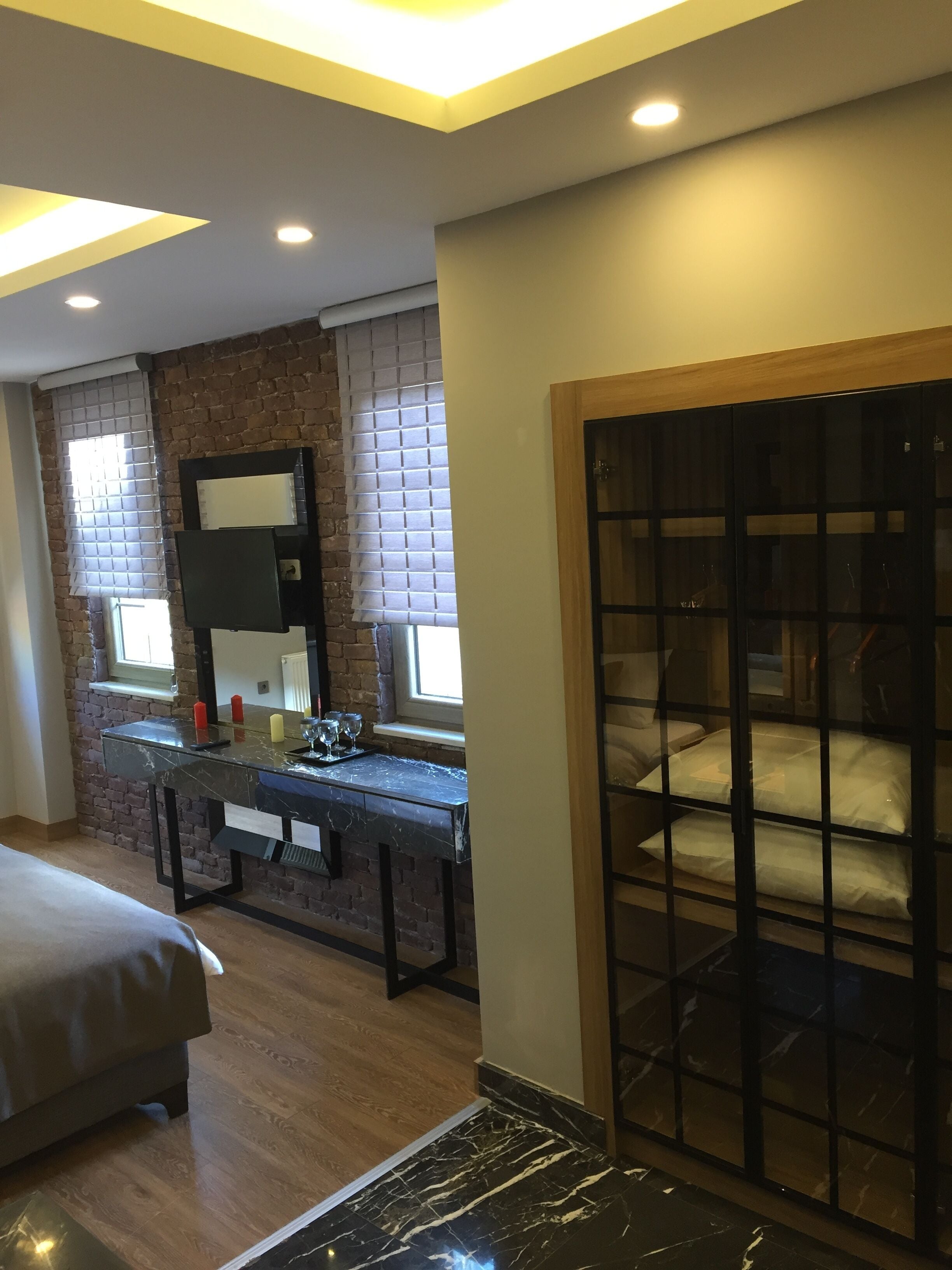 A modern bedroom with a bed, a desk with a mirror, and a wardrobe.