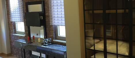 A modern bedroom with a bed, a desk with a mirror, and a wardrobe.