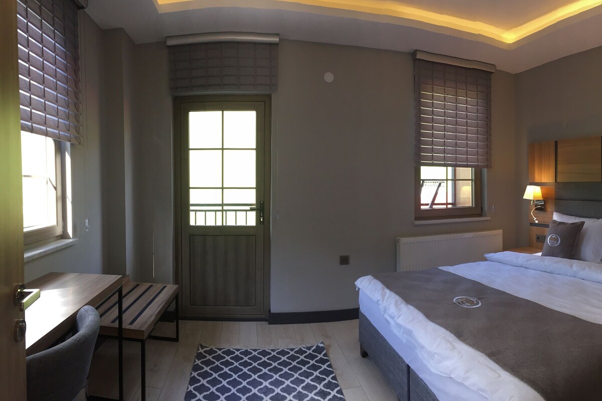 Ein Hotelzimmer mit Bett, Nachttischen, Schreibtisch, Stuhl, Fenster und Tür.