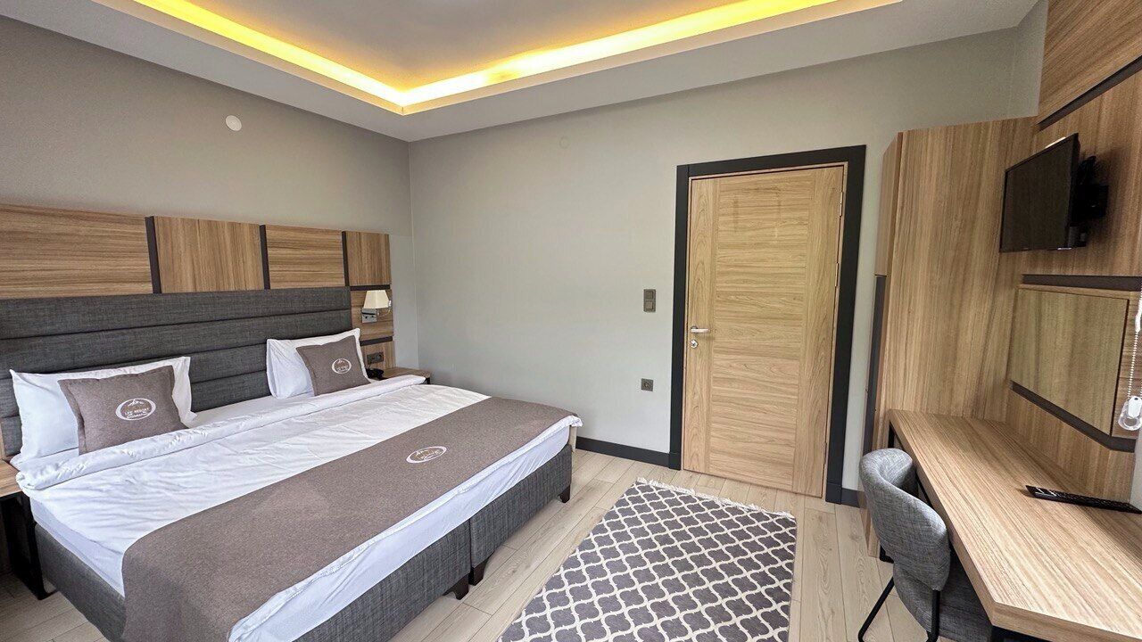 A modern hotel room with a large bed, a desk, and a TV.