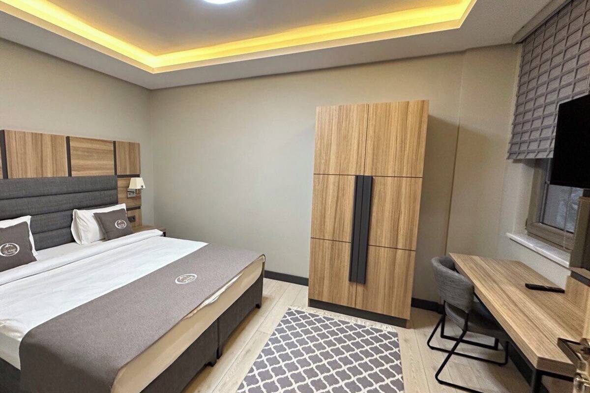 A modern bedroom with a bed, bedside tables, a wardrobe, a desk, and a chair.