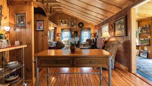 A cozy cabin interior with a wooden dining table, a sofa, and a chair. - Walk Softly, There’s a Dream Here! (Colchester)