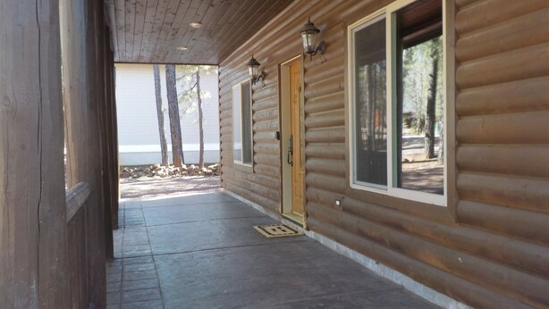 A wooden cabin with a covered porch, a door, and a window.
