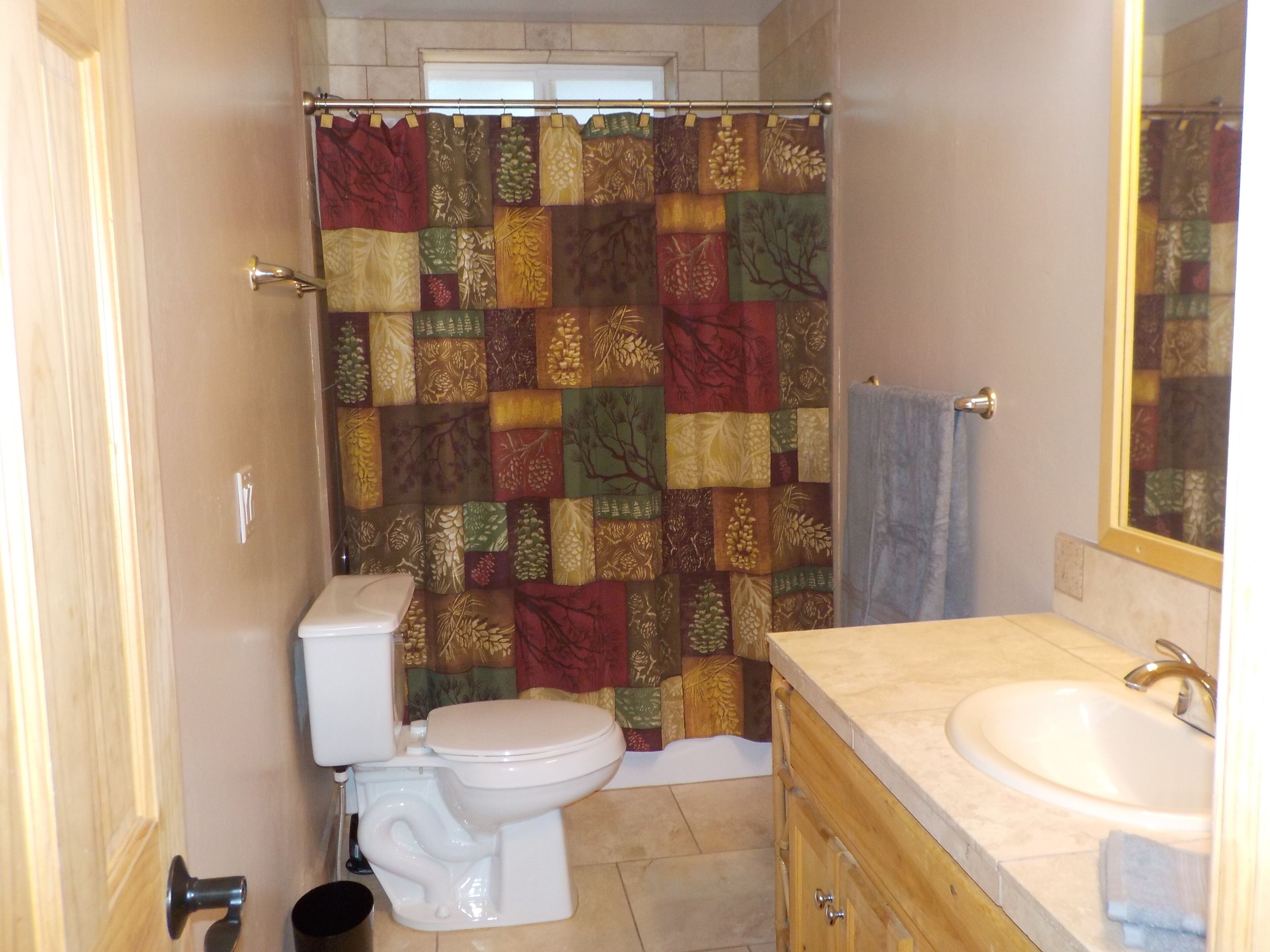 A bathroom with a toilet, sink, and a shower curtain with a patchwork design.
